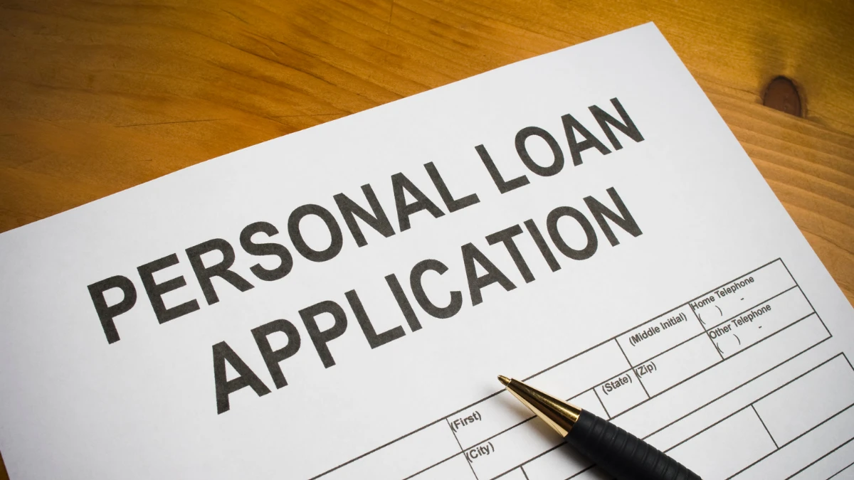 Personal loan application form on a wooden table with a pen