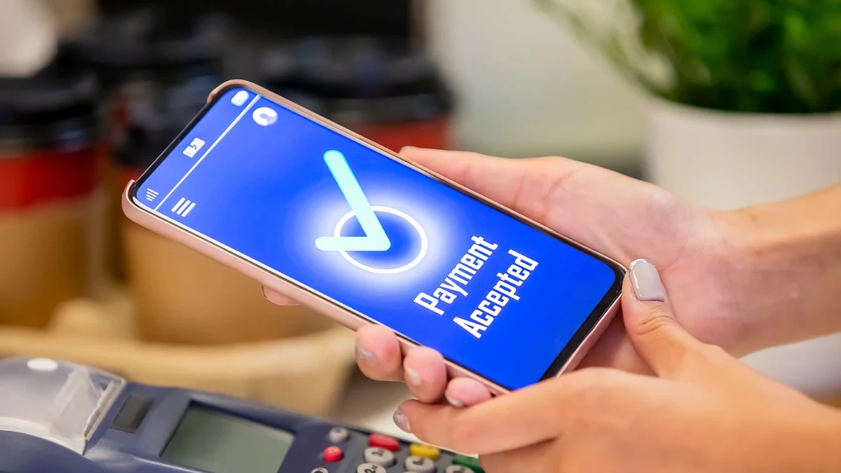 Concept of mobile payment apps showing a person using a smartphone and credit card to pay bills online.