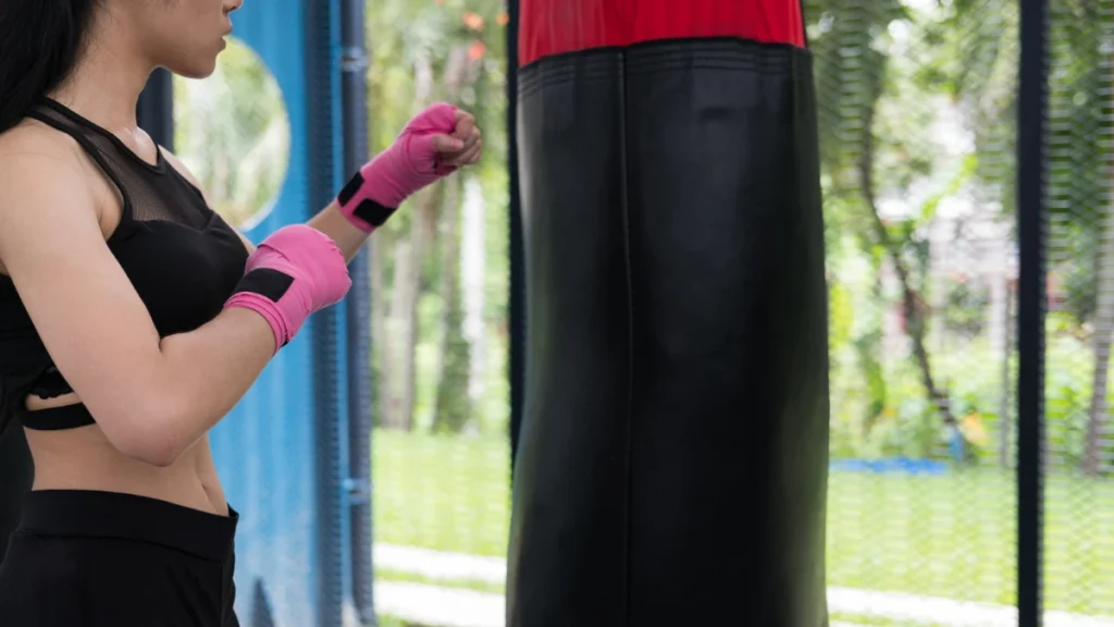 Female athlete hitting and punching sandbag