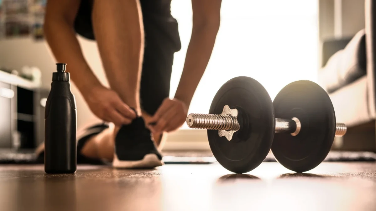 Man tying shoelaces inside a home gym.