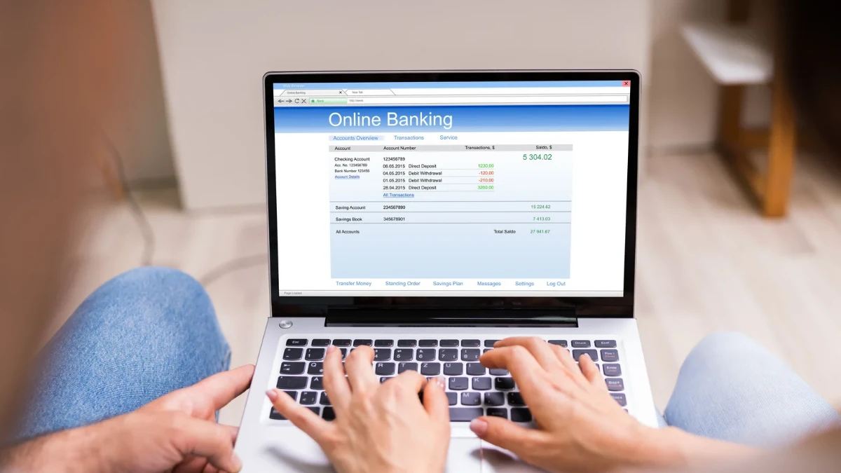 Couple reviewing their joint bank account online on a laptop, checking transactions and managing finances together.