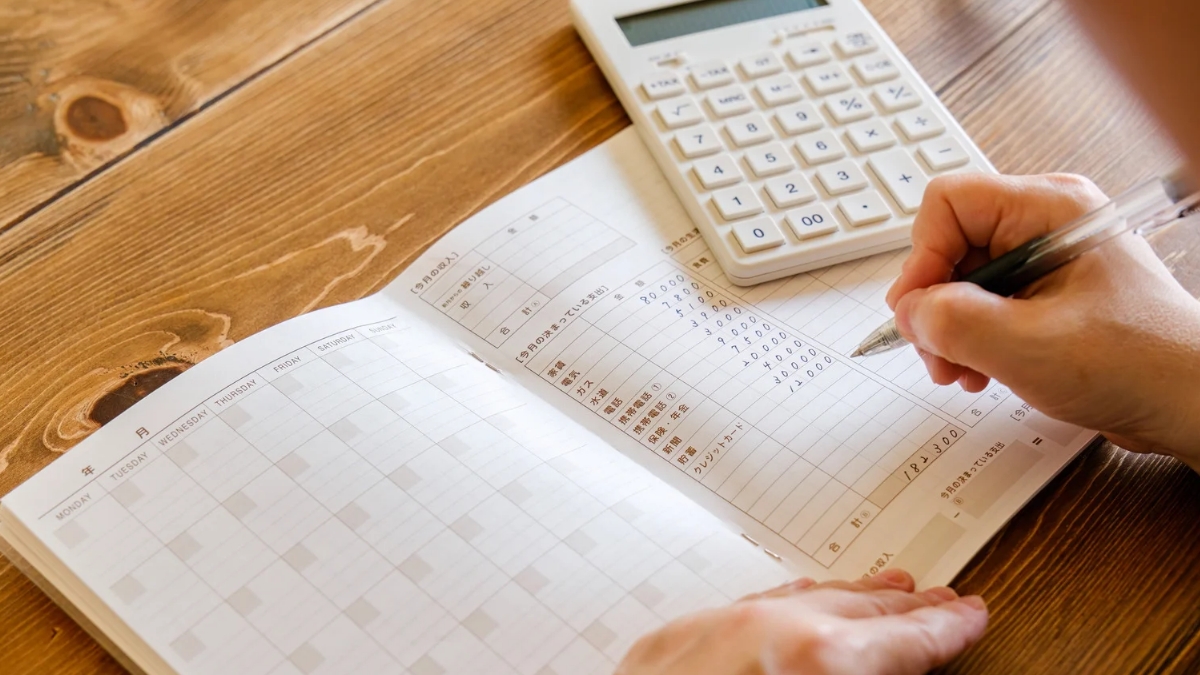 Household budgeting and saving money using a calculator and expense book