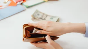 Person putting money in a brown wallet, illustrating the practice of saving money